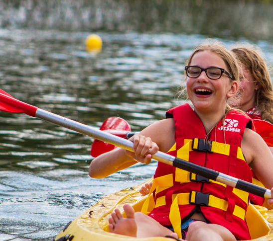 Twee meiden in een kano op het water bij Fun Beach in Midden-Limburg. Een leuke activiteit voor een sportdag, schoolreisje of personeelsuitje