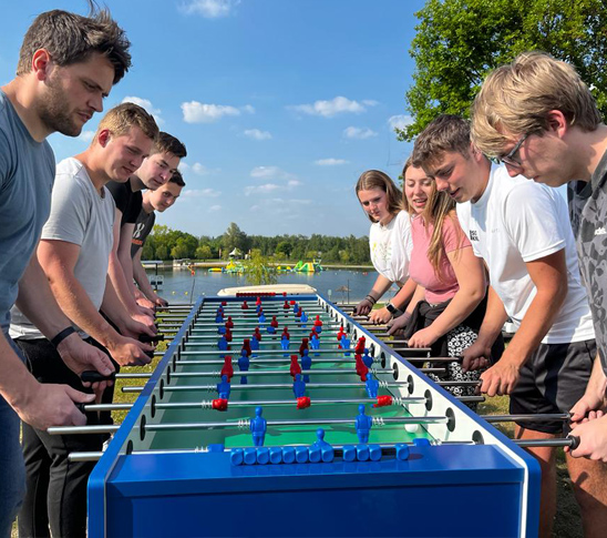 Een groep mensen speelt reuze tafelvoetbal tijdens een personeelsuitje bij Fun Beach in Midden-Limburg.