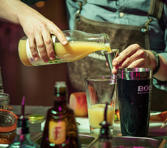 Een bartender doet de verschillende ingrediënten in een cocktailshaker tijdens de cocktailworkshop. Leuke activiteit voor een personeelsuitje of een vrijgezellenfeest.
