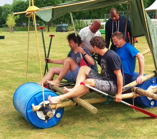 Mensen die in een flintstone auto van een berg afgaan tijdens een leuke teambuildingsdag.