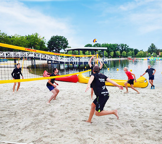 Een groep mensen die beachvolley speelt tijdens een sportdag op het strand van Fun Beach in Panheel, Limburg.