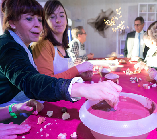 Twee dames die samen bonbons aan het maken zijn tijdens een chocoladeworkshop bij Fun Beach Group Events in Panheel, Limburg.