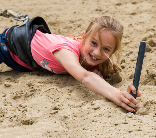 Een kind dat aan een bungeekoord vastzit en bungee run doet. Een leuke activiteit voor een sportdag of schoolreisje in Midden-Limburg.