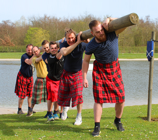 Mannen die deelnemen aan een activiteit van de schotse highland games. Goede teambuilding voor een vriendenweekend.