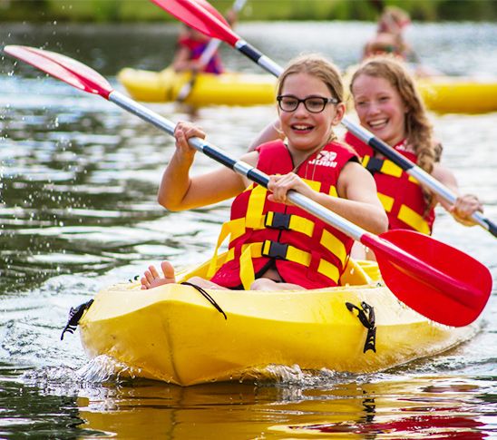 Twee meiden die kajakken tijdens de sportdag of schoolreis.