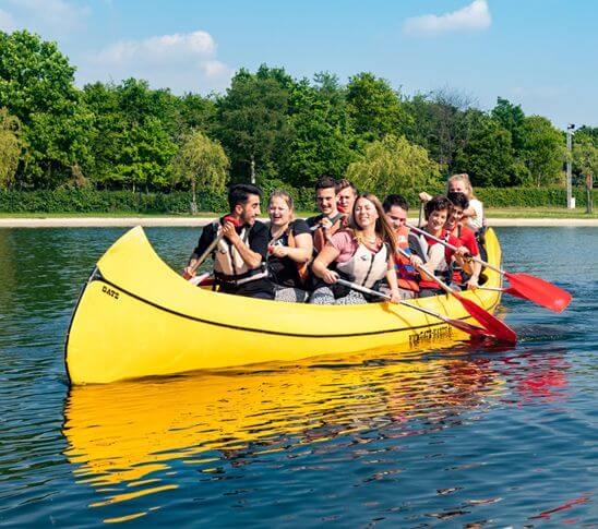 Groep mensen die deelnemen aan teambuilding door middel van een wateractiviteit, reuze kanoën.
