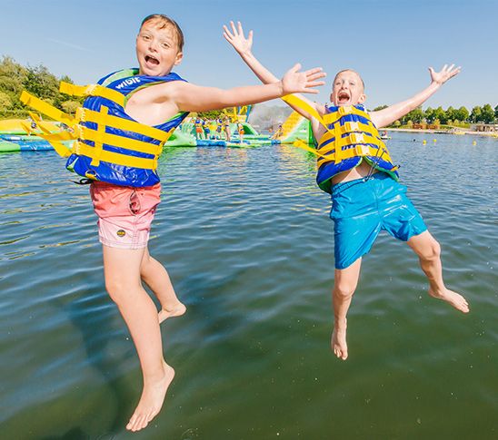 Kinderen die in het water springen tijdens het schoolreisje of de sportdag.